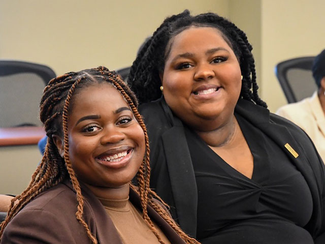 Law students smiling for photo in a lecture hall